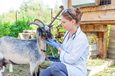 Side view of man with goat on field