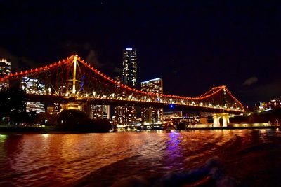 Low angle view of illuminated bridge over river at night