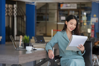 Portrait of young businesswoman using mobile phone while sitting in cafe