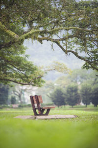 Close-up of chair on green landscape against sky