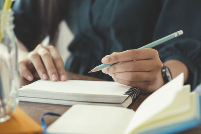 Close up hands with pen writing on notebook.