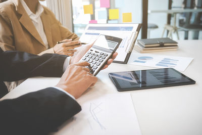 Midsection of business colleagues working on table