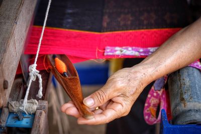 Cropped hand of woman holding needle by handloom at workshop