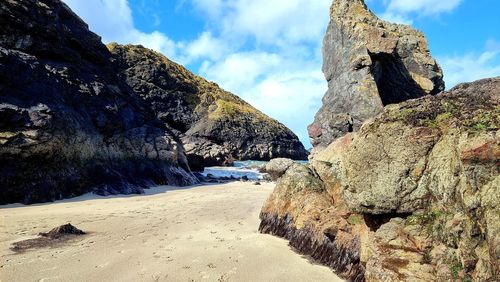 Rock formations on beach against sky