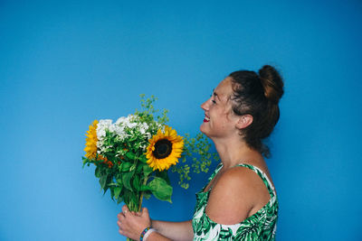Woman holding flowers against blue background