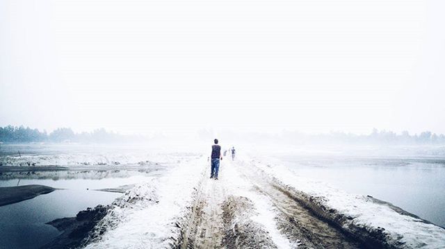 winter, snow, cold temperature, season, full length, lifestyles, clear sky, weather, tranquil scene, rear view, leisure activity, walking, beauty in nature, scenics, nature, tranquility, water, copy space