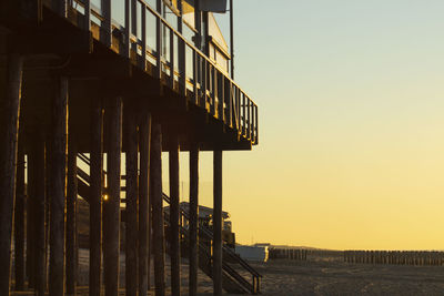 Built structure by sea against clear sky during sunset