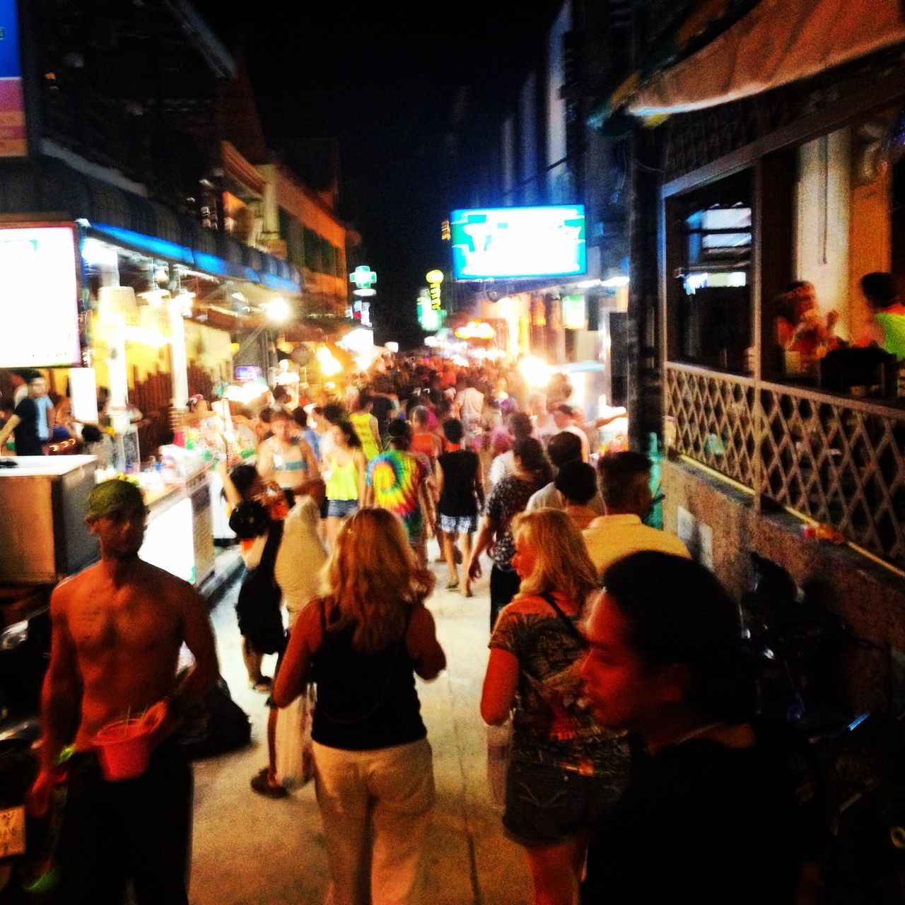 night, illuminated, men, large group of people, lifestyles, person, crowd, street, city, city life, leisure activity, building exterior, market, walking, standing, architecture, lighting equipment, built structure, rear view