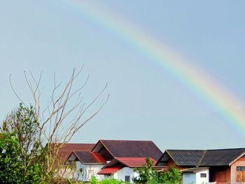 Low angle view of rainbow over buildings against sky