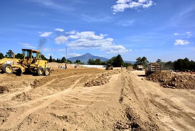 Panoramic view of dirt road on field against sky