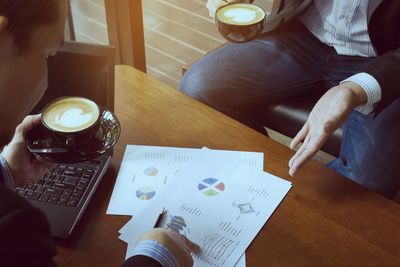 High angle view of businessman discussing graphs with coworker in office