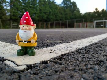 Close-up of figurine on road against trees