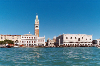 Buildings in city against clear blue sky