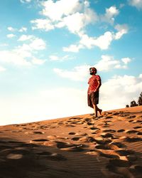 Rear view of man walking on sand