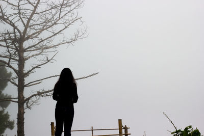 Rear view of silhouette woman standing against sky