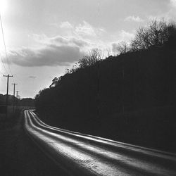 Railroad tracks by road against sky