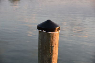 Close-up of wooden post in lake during sunset