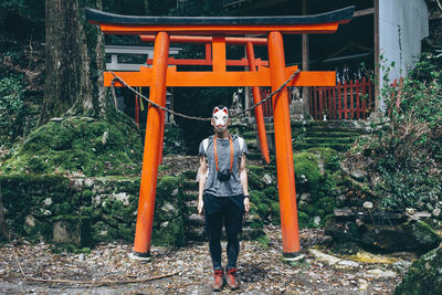 Portrait of young woman standing against trees