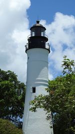 Low angle view of lighthouse by building against sky