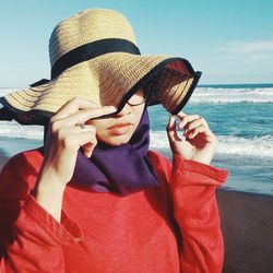 Portrait of woman holding hat on beach