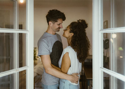 Side view of smiling couple looking at each other seen through doorway
