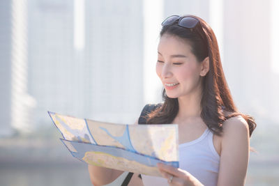 Female tourist reading map while standing in city