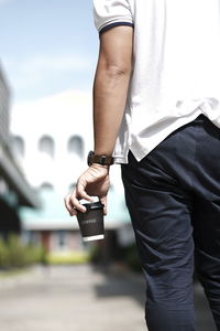 Midsection of man holding coffee cup outdoors