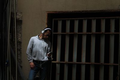 Man using phone while standing by wall