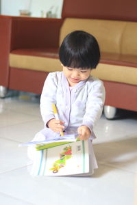 Girl holding book in living room at home