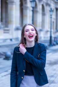 Cheerful woman standing against building in city