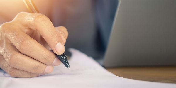 Midsection of woman writing in book