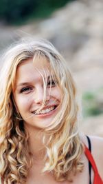 Close-up portrait of smiling young woman with blond air