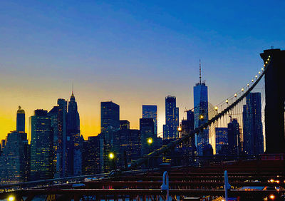 Illuminated buildings against blue sky at dusk