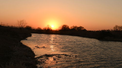 Scenic view of lake against orange sky