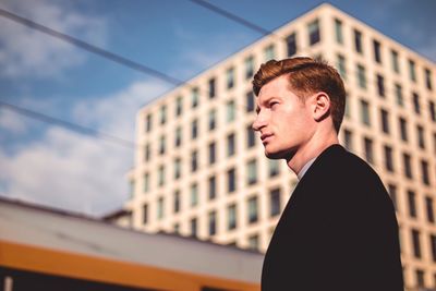 Portrait of young man standing against building in city