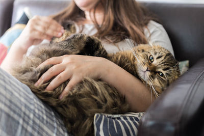 Midsection of woman with cat relaxing on bed