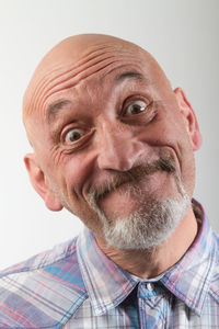 Close-up portrait of smiling senior man against white background