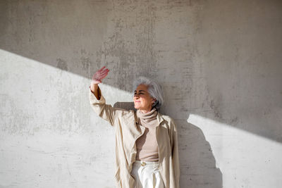 Woman looking away while standing in front of wall during sunny day