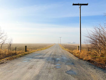 Road amidst field against sky