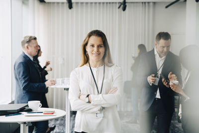 Portrait of confident businesswoman with arms crossed standing at workplace