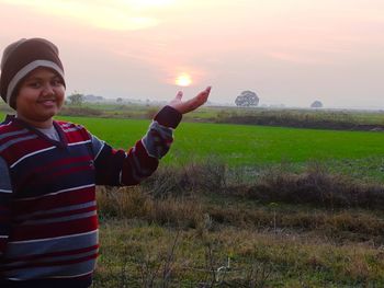 Portrait of smiling man standing on field during sunset