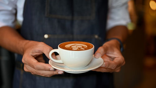 Midsection of man holding coffee cup