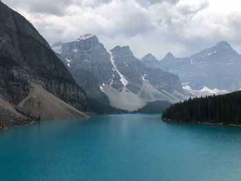 Scenic view of lake by mountains against cloudy sky