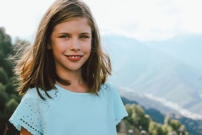 Portrait of smiling girl standing against mountains