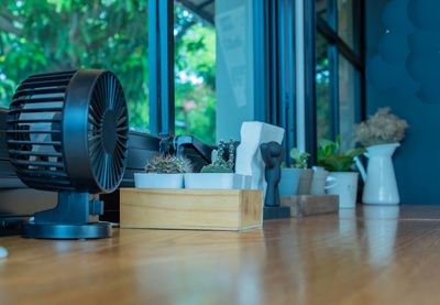 Exhaust fan and potted plants on table at home