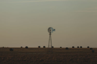 Hay bales on field against clear sky