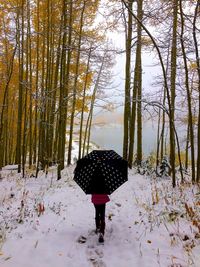 Rear view of woman walking on snow covered field