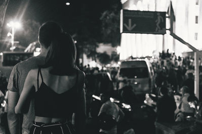 Rear view of people standing on street at night