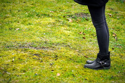 Low section of woman standing on grassy field