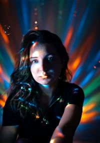 Portrait of young woman against illuminated lights